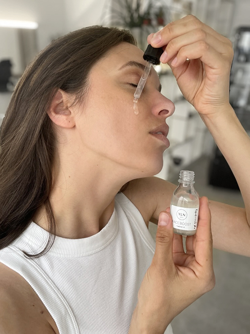Frau gibt sich einen Pipettenstoß des hyaluronsäure Serums von YLN auf die Gesichtshaut und verteil es dann im Gesicht